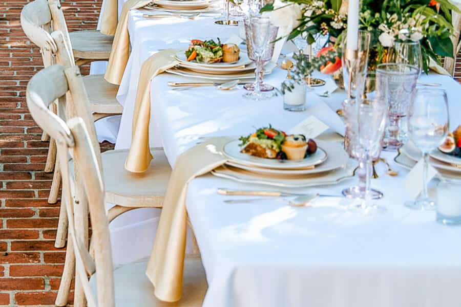 wedding table setting with white linen tablecloth and gold napkins