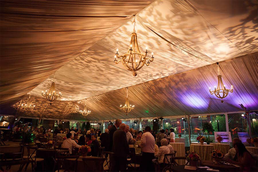 elegant wedding reception inside outdoor frame tent with decorative lighting and furniture