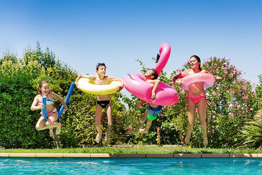 kids jumping in pool with floaties
