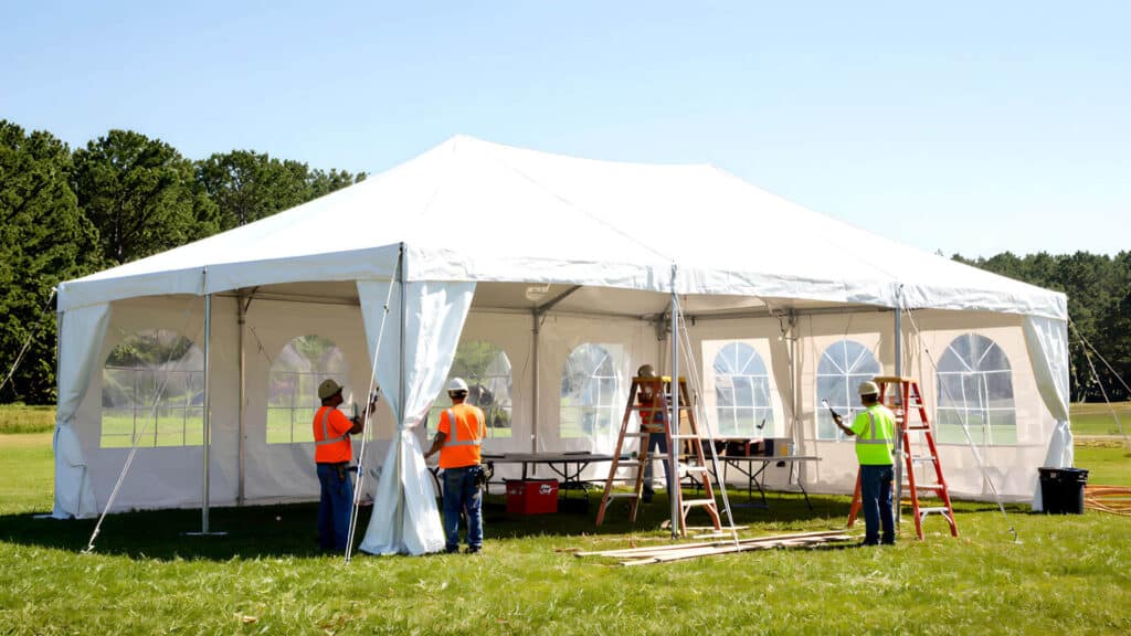 event rental workers setting up rental tent for outdoor party